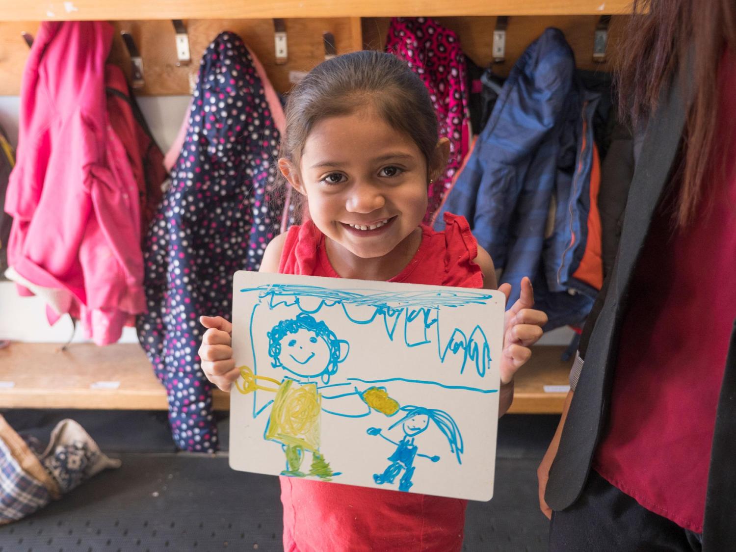 Kindergarten student holding up her drawing